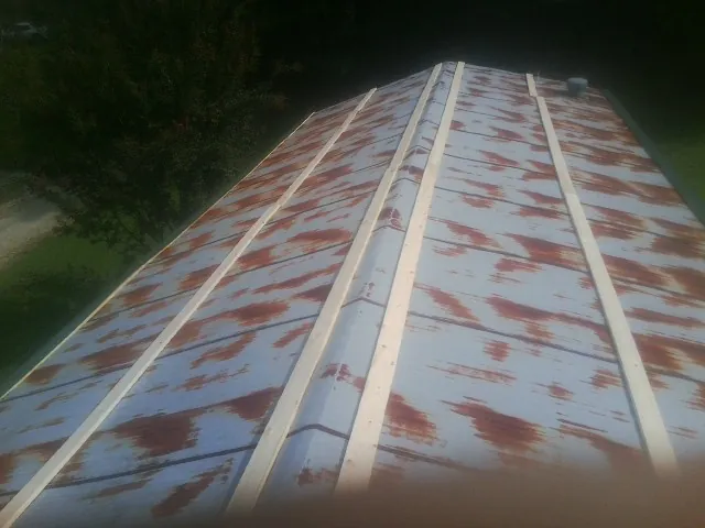 Rusted metal roof panels with new wood purlins before replacement in Corral