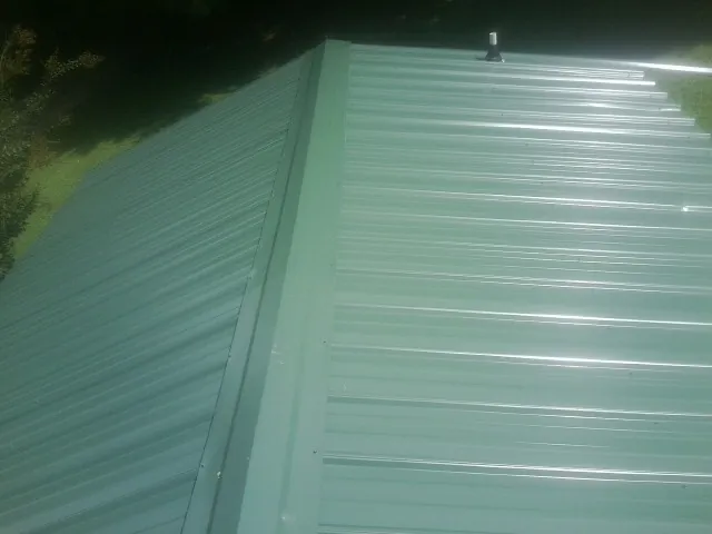 New green metal panels meeting at the ridge of a roof — Flat Roof Repair work by our crew in Corral