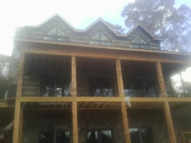 Dormers and porch framing on a large log home under construction — Roof Coating work by our crew in Corral