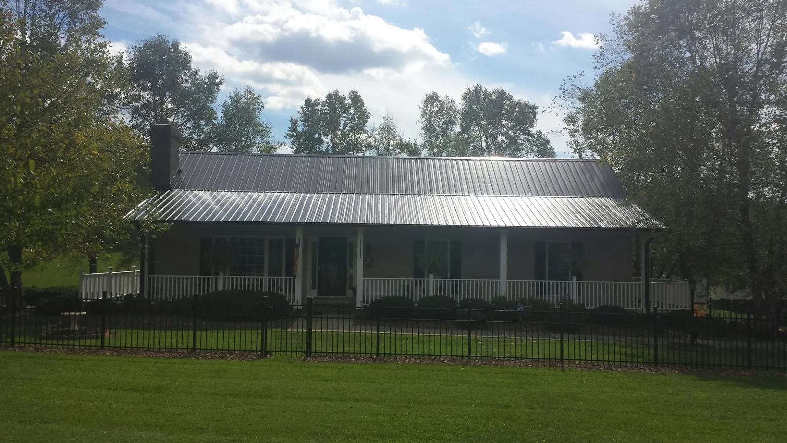 Gray metal roof on a brick ranch with a full width front porch — Gutter Guard Installation work by our crew in Corral