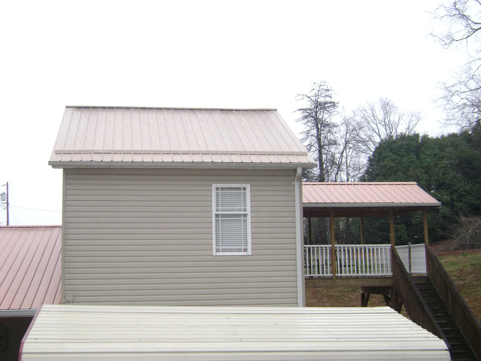 Tan metal roofs on a two story addition and attached porch, from a Roof Replacement job in Corral