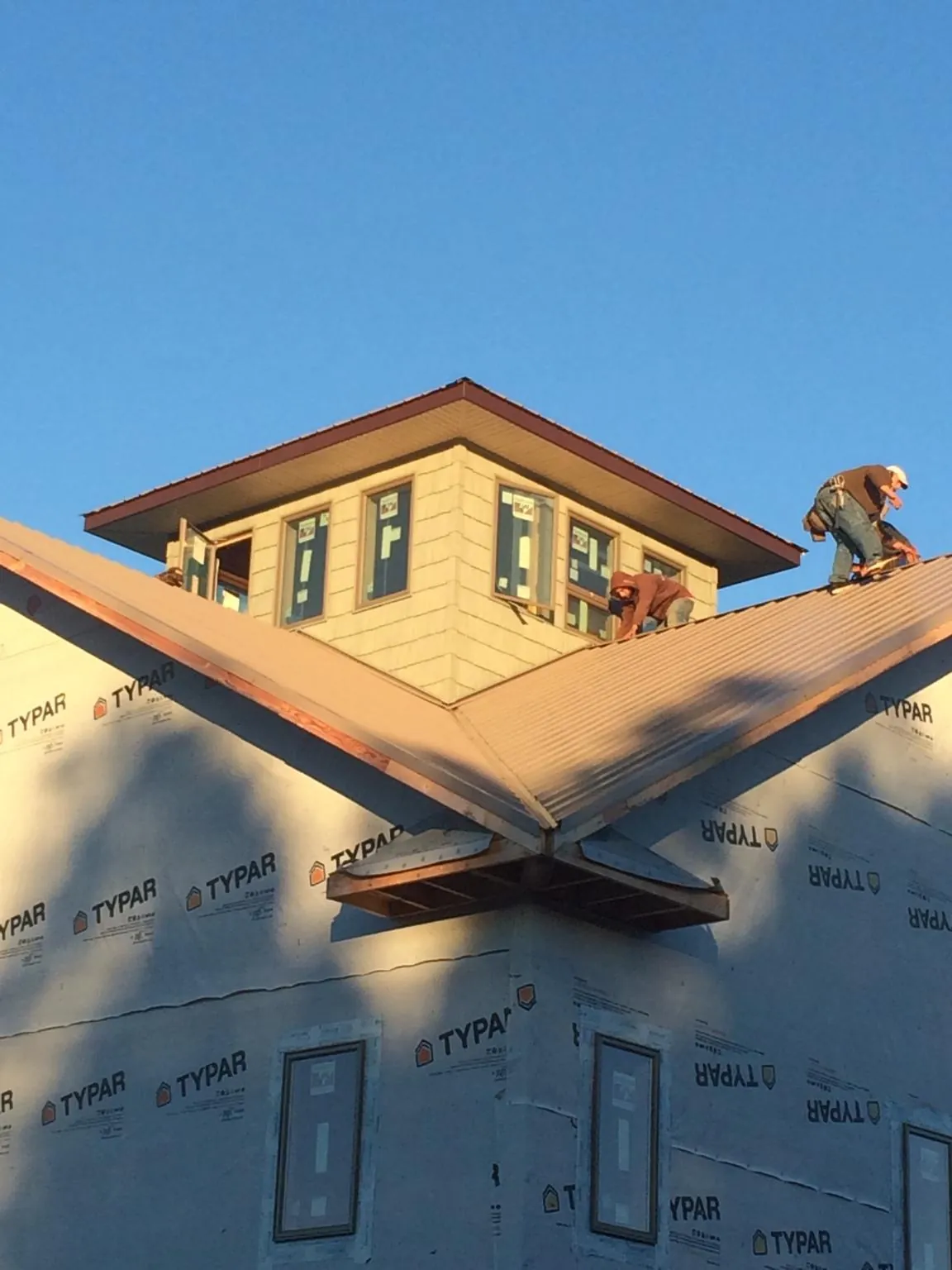Roofers working around a rooftop cupola on a new metal roof at sunset — Roof Waterproofing in Corral by Roofing Brothers
